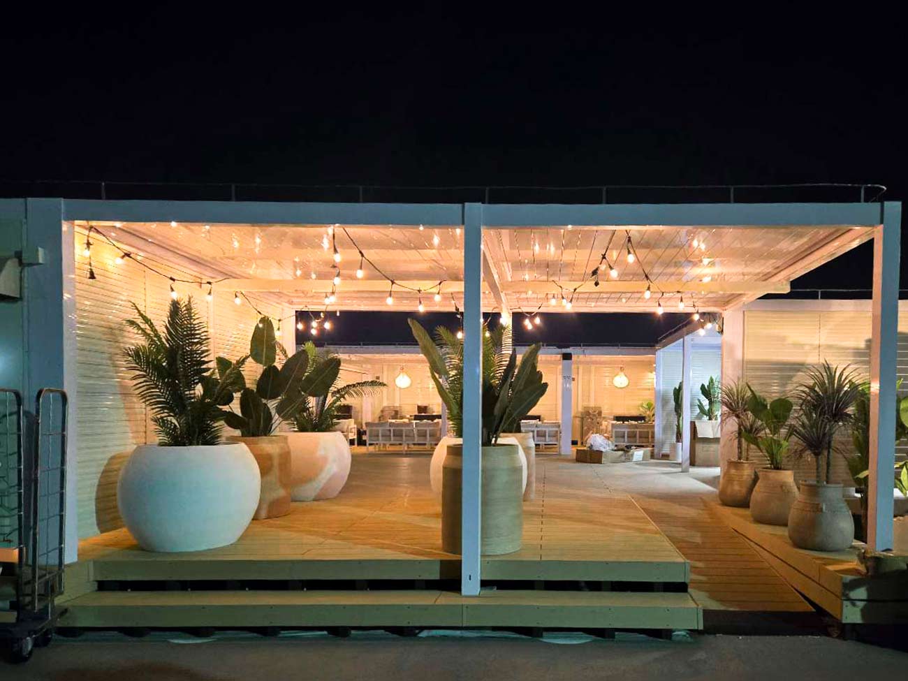 ライトアップされた観葉植物とストリングライトが印象的な屋上BBQテラスの夜の外観