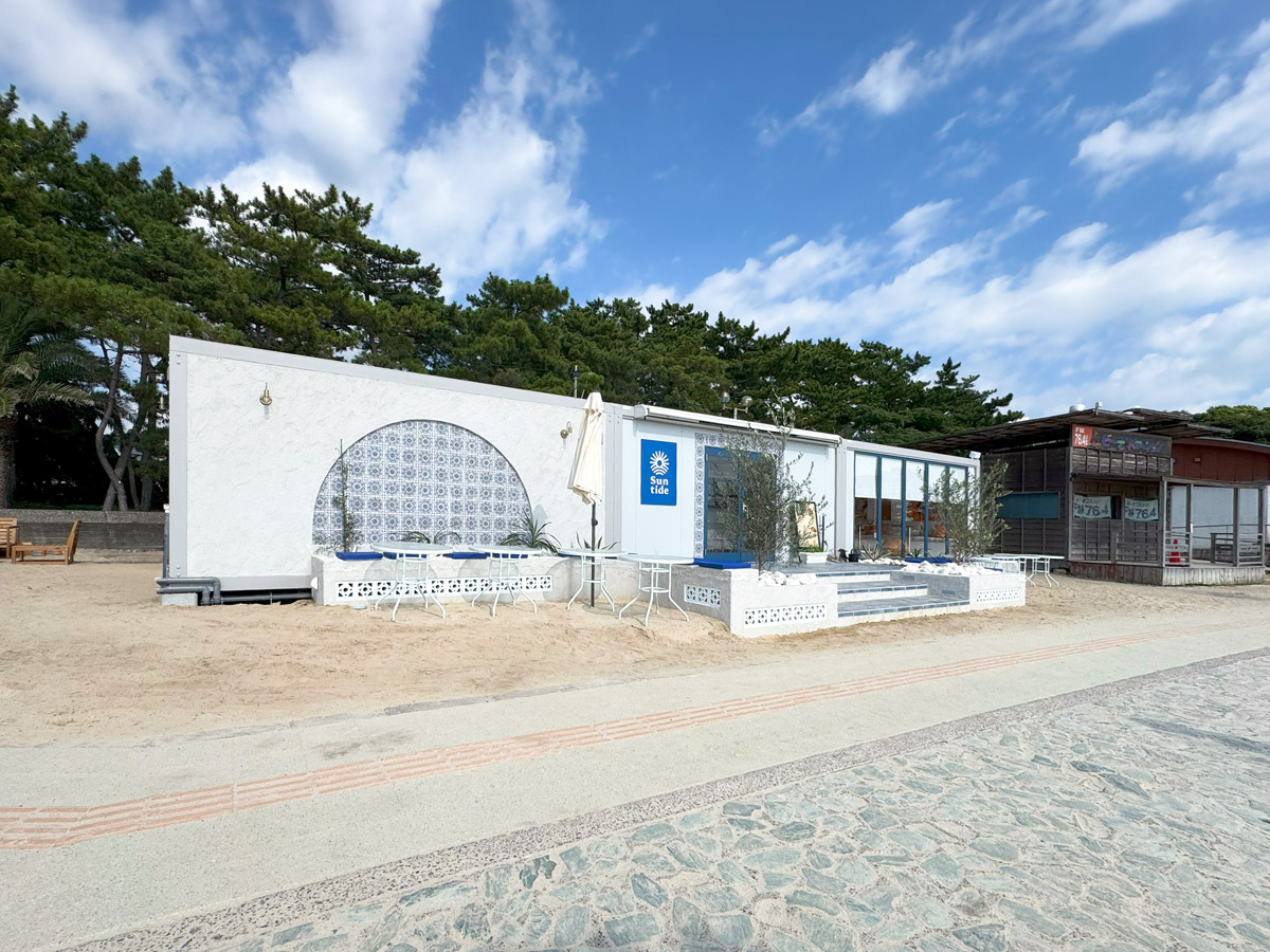 青と白を基調にした外観、アール状タイルとベンチが印象的なSuntide Cafe & Barの正面