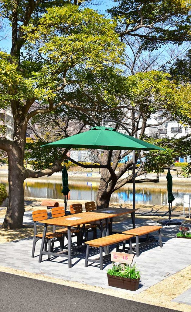THE RIVERSIDE BBQ NISHIKASAI 水辺のBBQテラス - 河川敷に設置された緑に囲まれたダイニングエリア。DEPOSグリーンパラソル完備で、自然を感じる快適なアウトドアダイニング空間を実現。東京都江戸川区の最新BBQ施設の導入事例