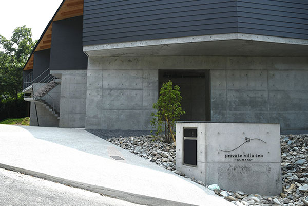 コンクリート壁と栗石敷きが調和したprivate villa tenの建物外観とサイン