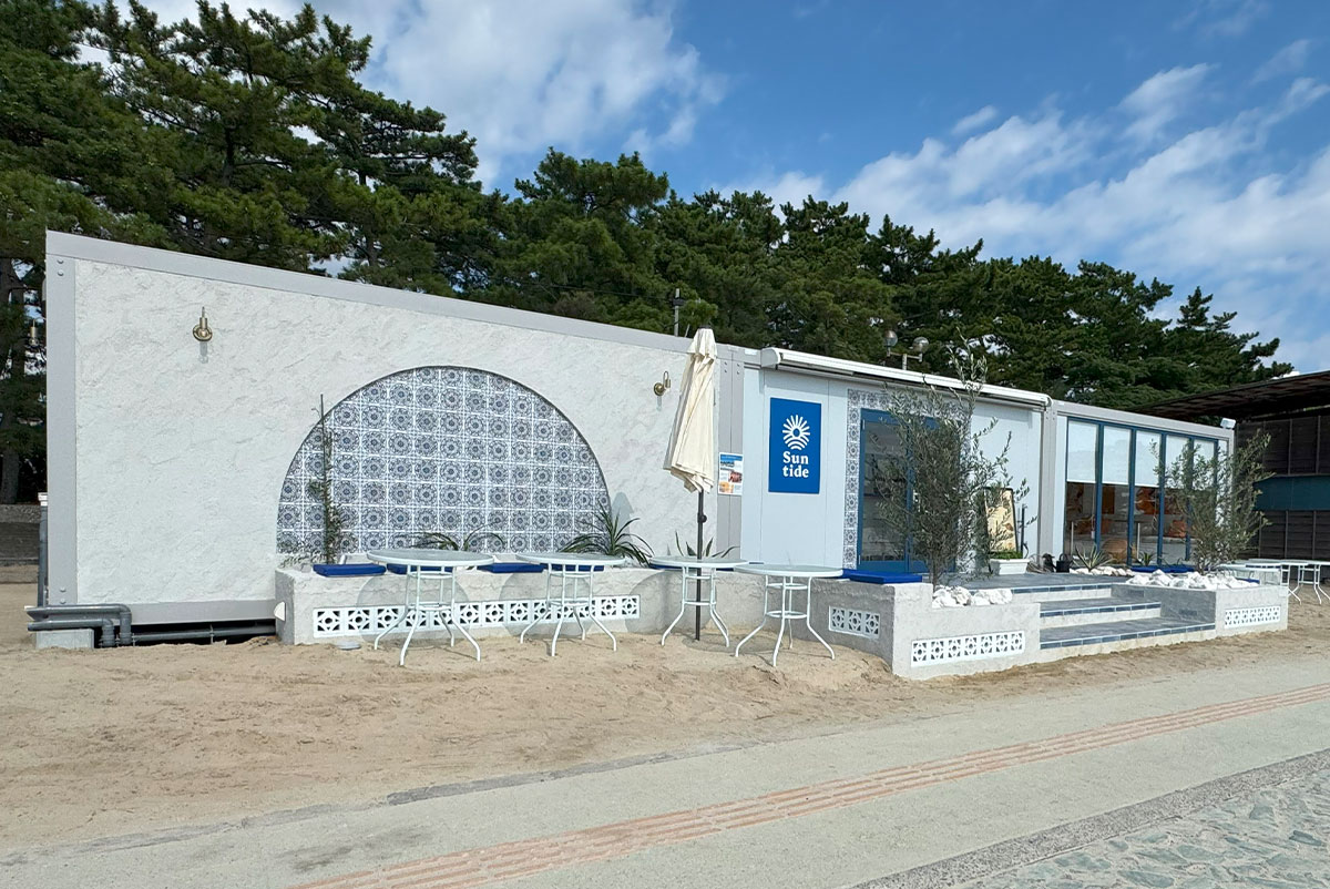 青と白を基調にした外観、アール状タイルとベンチが印象的なSuntide Cafe & Barの正面