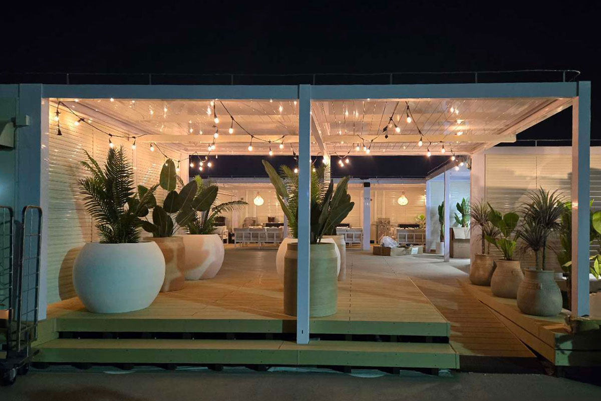 ライトアップされた観葉植物とストリングライトが印象的な屋上BBQテラスの夜の外観